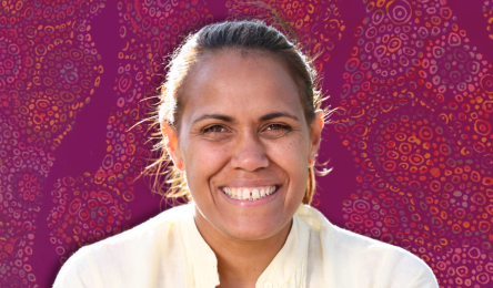 Portrait photo of Cathy Freeman with a red background and inidgenous artwork