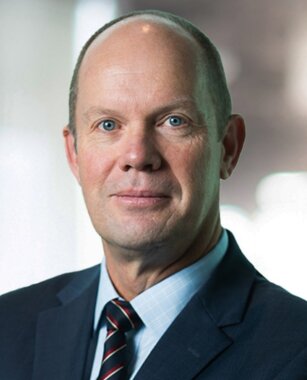 Portrait photo of Andrew Watson in a black suit with blue shirt and maroon tie